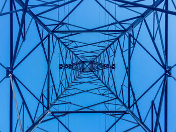 Low angle view of electricity pylon against clear blue sky