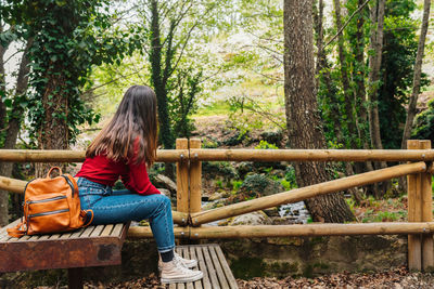 Woman sitting on seat in forest