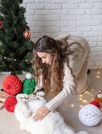 Young attractive woman decorating the christmas tree and playing with dogs