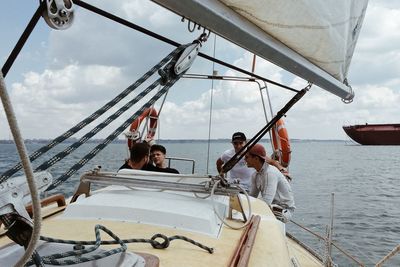 People in boat sailing on sea against sky