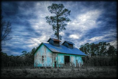 Barn on field against cloudy sky