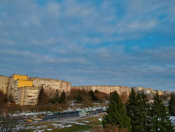 Buildings by road against sky in city