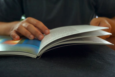 Close-up of human hands holding book on table