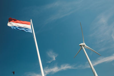 Low angle view of windmill and dutch flag against sky