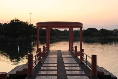 Pier over lake against sky during sunset