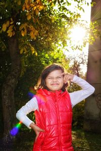 Cute girl making face while standing against trees