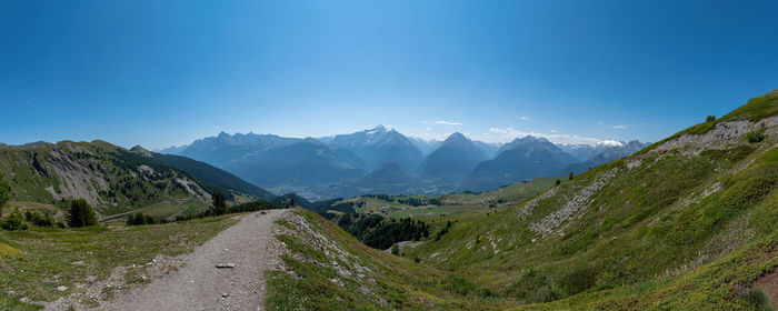 Road leading towards mountains against blue sky