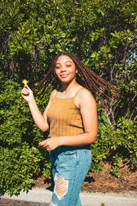 Portrait of a smiling young woman standing against plants