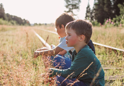 People sitting on railroad track by plants