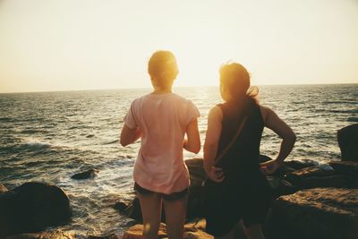 Rear view of friends standing at rocky shore