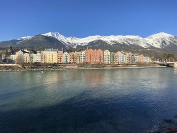 Scenic view of river by buildings against clear blue sky