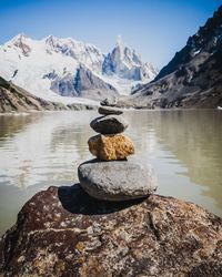 Stack of stones in lake by mountain against sky