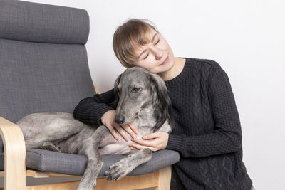 Young woman with dog sitting on sofa