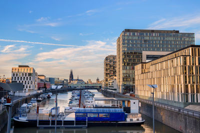 Boats moored in canal by buildings against sky in city