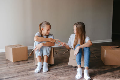 Side view of mother and daughter standing against wall