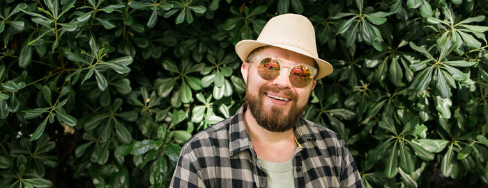 Portrait of young man wearing hat against plants