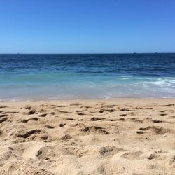 Scenic view of beach against clear blue sky