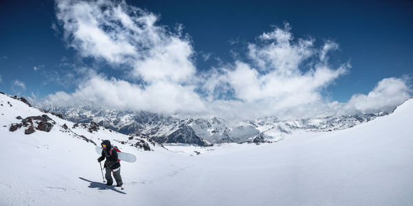 Woman snowboarder freerider climb up the fresh snow riding backcountry. peaks of mountains 