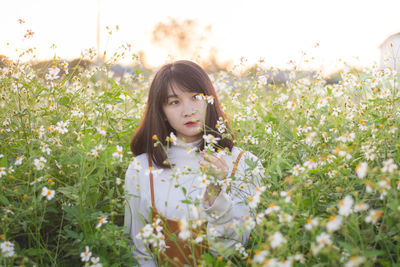 Portrait of woman on flower field against sky