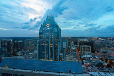 Modern buildings in city against cloudy sky