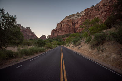 Road leading towards mountains against sky