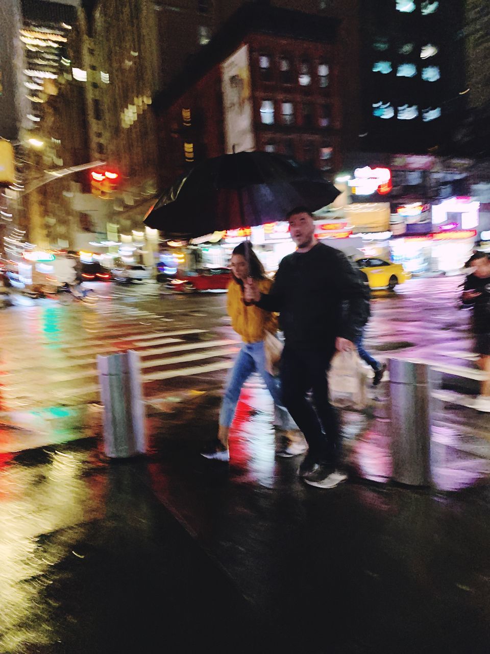 city, street, night, motion, blurred motion, architecture, transportation, city life, building exterior, real people, built structure, illuminated, men, mode of transportation, walking, two people, women, road, people, leisure activity, city street, outdoors, riding, rain