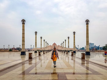 Woman walking on city street against sky