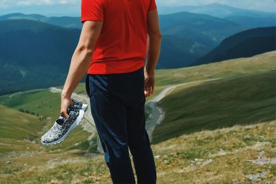 Rear view of man standing on mountain against sky