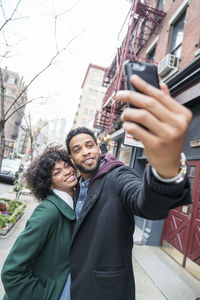 Business couple taking selfie while standing in city