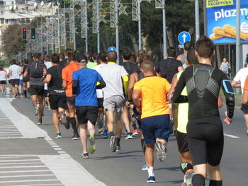 Rear view of people walking on street in city