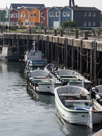 Fishing boats moored at harbor by buildings in city