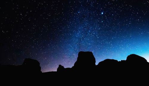 Low angle view of silhouette rocks against sky at night