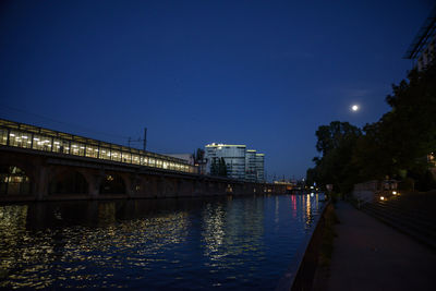 Illuminated bridge over river against sky at night