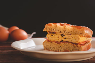 Close-up of bread in plate on table against black background