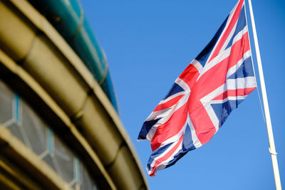 Low angle view of union jack flag against blue sky in eastbourne