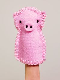 Close-up of hand holding pink toy against white background