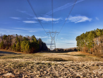 Electricity pylon on field against sky