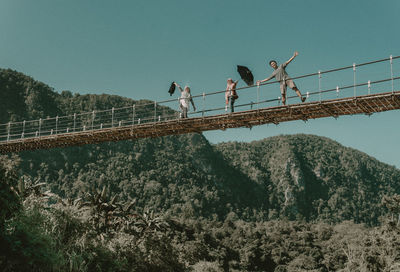 Low angle view of people walking on footbridge