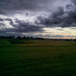 Scenic view of grassy field against cloudy sky