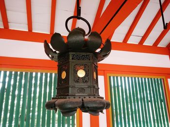 Low angle view of electric lamp hanging against orange wall