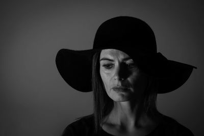 Close-up of woman wearing hat against gray background