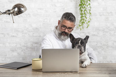 Freelance man working from home with his dog sitting in the office.