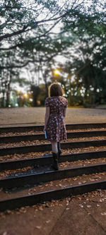 Rear view of woman standing on railroad track