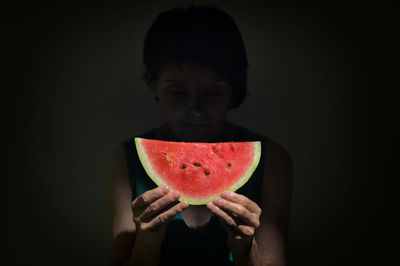 Woman holding slice of a red watermelon in studio