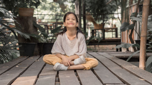 Portrait of girl sitting on wood