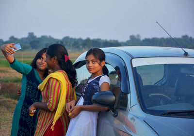 Friends on car against sky
