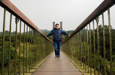 Full length portrait of man standing on footbridge