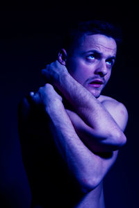 Portrait of young man against black background