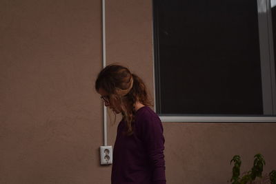 Side view of woman standing against wall