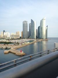 Sea by modern buildings against sky in city